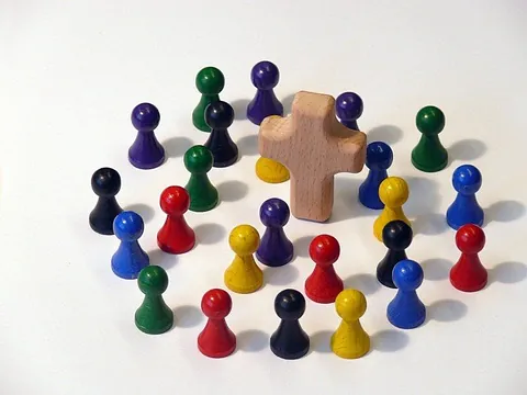 Symbolbild Hauskreise - Spielfiguren kreisförmig um ein Holzkreuz stehend